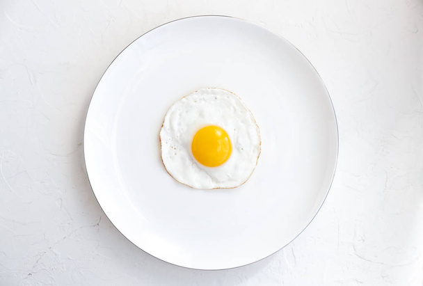 Жареное яйцо на белом фоне, вид сверху
 - Фото, изображение
