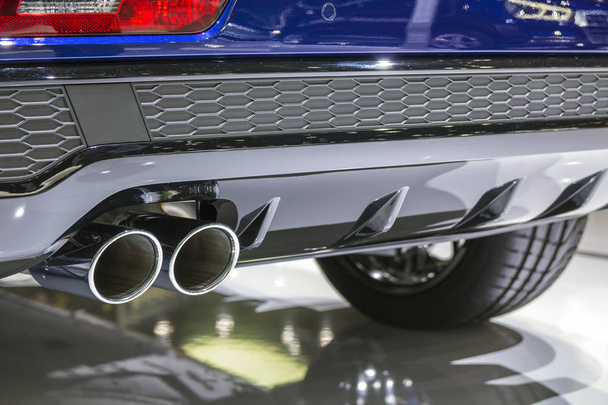 Подвійна хромова вихлопна труба потужного спортивного автомобіля з сірими пластиковими деталями
 - Фото, зображення