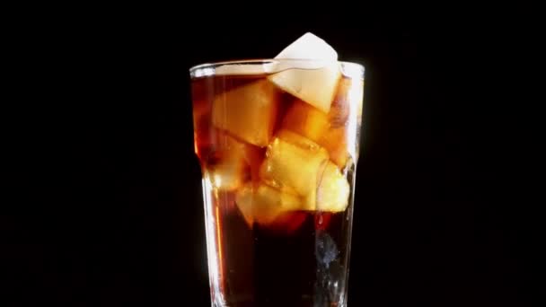 Cola com bolhas derramadas em um copo de gelo.Fundo preto
 - Filmagem, Vídeo