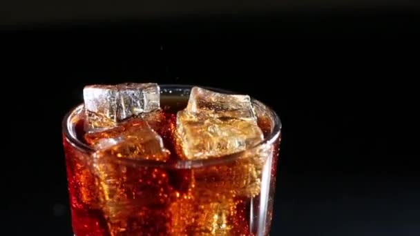 Cola buborékok öntötte egy pohár jég. Fekete háttér - Felvétel, videó