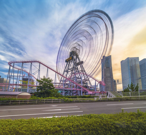 View from Kokusai bridge of Cosmo Clock 21 Big Wheel at Cosmo World Theme Park, overlooking the Diving Coaster Vanish in the Minato Mirai district of Yokohama with the Landmark Tower in the sunset summer sky. - Photo, Image