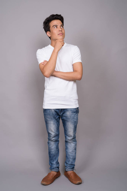 Portrait of young Asian man against gray background - Foto, imagen
