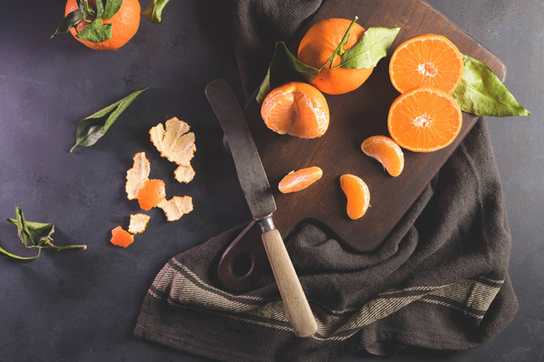 Fresh mandarin oranges or tangerines with leaves on textured dark background - Foto, Imagen