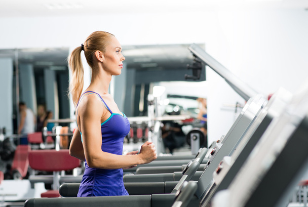 attractive young woman runs on a treadmill - Foto, Bild