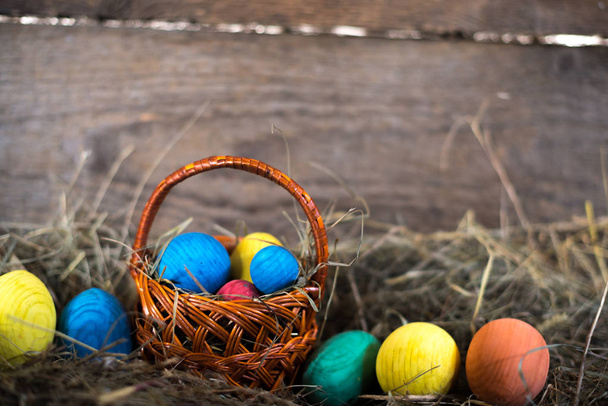 Pasen eieren in een mand op een hooi met een onscherpe achtergrond - Foto, afbeelding