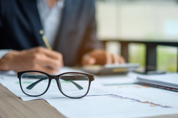 Close up eye glassess with Businessman analysis maketing plan background, Accountant calculate financial report with graph chart.  Business, Finance and Accounting concepts - Foto, imagen