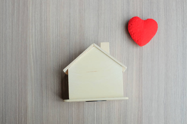 Κόκκινη καρδιά και ξύλινο σπίτι μοντέλο. Το κατάλυμα ασφαλιστικό και Κτηματομεσιτικό έννοιες - Φωτογραφία, εικόνα