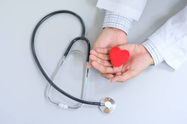 Muž Doktor s stetoskop ruka drží tvar červené srdce v nemocnici. Koncepce zdravotnictví a zdravé pojištění - Fotografie, Obrázek