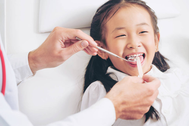 Amistoso dentista joven examinando los dientes infantiles felices en la clínica dental. Concepto odontológico
. - Foto, Imagen