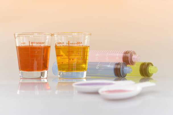 Лікувальна чашка, пероральний шприц і чайна ложка, наповнені ліками від перорального сиропу
. - Фото, зображення