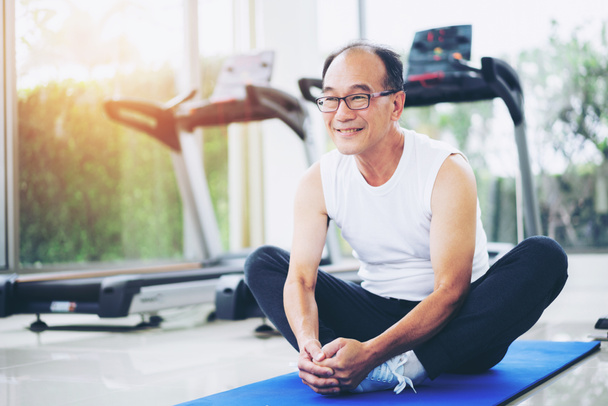 Senior man do body stretching in fitness center. Healthy lifestyle. - Photo, Image