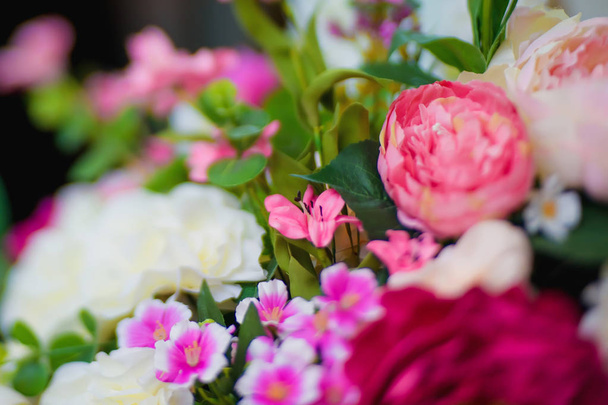 Μπουκέτα με διακοσμητικά λουλούδια. Ροζ, μοβ, λευκά λουλούδια. Ψεύτικα λουλούδια για το εσωτερικό. Διακοσμώντας με τα τεχνητά λουλούδια. Ανθοπωλεία. - Φωτογραφία, εικόνα