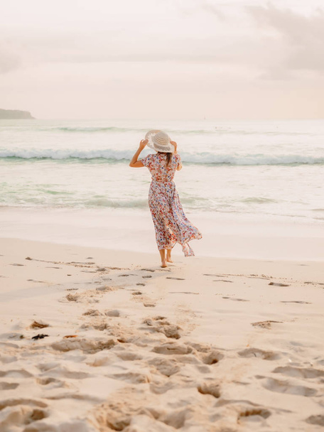 Aantrekkelijke vrouw in mooie jurk op strand bij zonsondergang of zonsopgang. Vrouwelijke stijl. - Foto, afbeelding