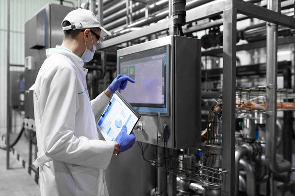 Technologe macht sich Notizen, während er in der Produktionsabteilung der Milchfabrik steht - Foto, Bild