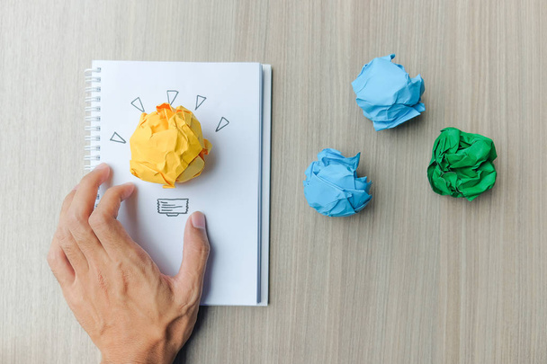 Mão segurando papel enrugado colorido na mesa de madeira. Novos conceitos de Ideia, Criatividade, Gênio e Inovação
 - Foto, Imagem