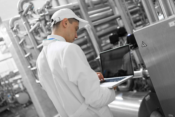 Süt fabrikasında onun elinde bir dizüstü bilgisayar ile teknoloji uzmanı - Fotoğraf, Görsel