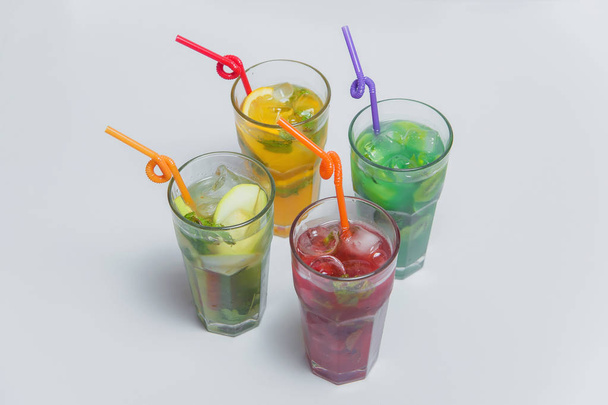 Apple, tropical, berry, fruit lemonade. Refreshing drinks with ice. Cold cocktails in glass cups. Bright colored drinks. Lemonades in glasses on a white background. - Photo, Image