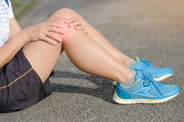 Young fitness woman holding his sports leg injury, muscle painful during training. Asian runner having knee ache and problem after running and exercise outside in summer - Fotó, kép