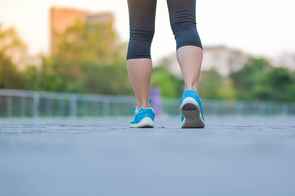piernas de mujer fitness joven caminando en el parque al aire libre, corredor femenino corriendo en el camino fuera, atleta asiática trotando y ejercicio en el sendero en la mañana del sol. Conceptos de deporte, salud y bienestar
 - Foto, imagen