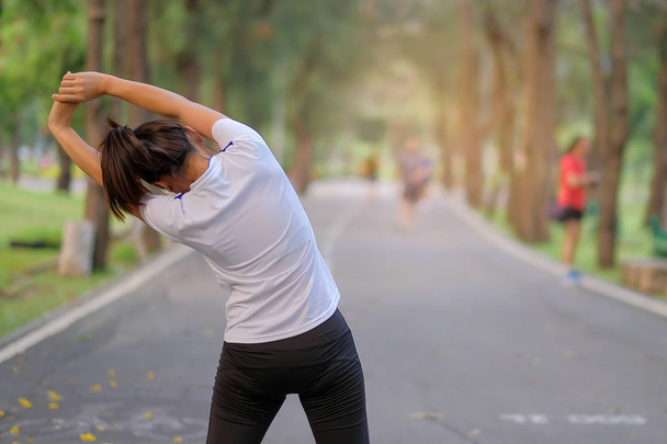 Mladý sportovec žena protažením v parku venkovní, ženské runner zahřátí připraven k běhání na silnici u asijské Fitness walking a cvičení na chodník v ráno. koncepce wellness a sport - Fotografie, Obrázek