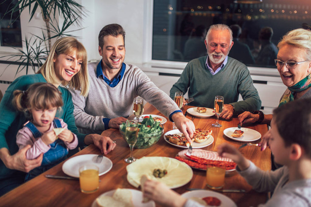 多世代家族の家でテーブルを囲んで食事を楽しむ  - 写真・画像