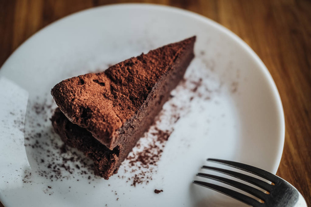 One slice of vegan chocolate brownie cake on wooden table. Sugar free, wheat free, dairy free, flourless dessert. Dark mood food photo. Healthy eating, lifestyle concept. Copy space - Photo, Image
