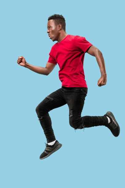 Freedom in moving and forward motion. The happy surprised young afro man jumping - Foto, imagen