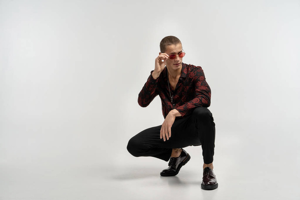 Casual dressed young man in black jeans crouched and posing - Foto, Imagem