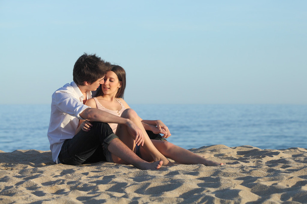 Couple flirting sitting on the sand of the beach - Φωτογραφία, εικόνα