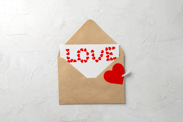 Valentines concept minimal, cadeau fait main enveloppe artisanale, note d'amour, mot amour fait de petits coeurs de papier rouge sur fond gris
 - Photo, image