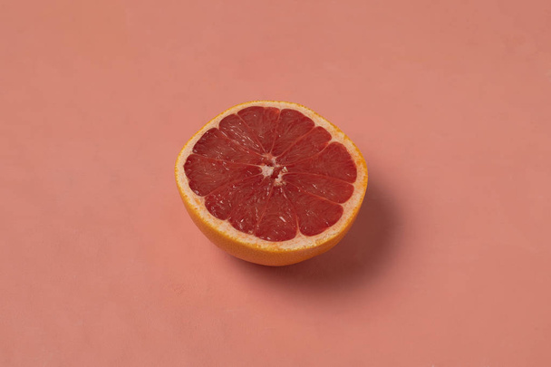 Half of ripe pink grapefruit on living coral background color year 2019, top view, copy space - Фото, изображение