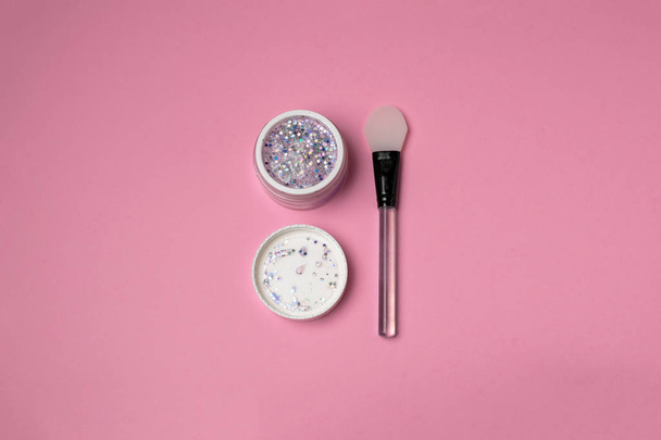 Hautpflege Beauty Minimalkonzept - trendige Glitzergesichtsmaske mit Silikonspachtel von oben, rosa Hintergrund, Kopierraum. Bloggen, soziale Medien. - Foto, Bild
