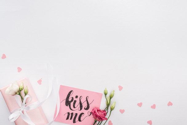 top view of flowers, gift box and card with 'kiss me' lettering isolated on white - Photo, Image