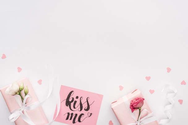 Ansicht von Geschenkboxen, Papierherzen und Karte mit "Kiss me" Schriftzug isoliert auf weiß - Foto, Bild