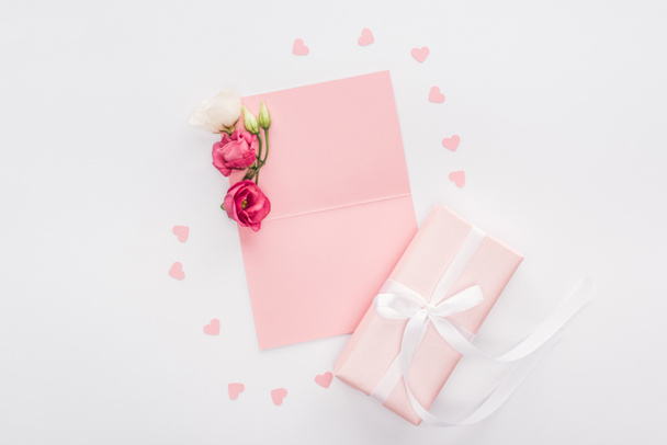top view of empty card, paper hearts and gift box isolated on white - Photo, Image