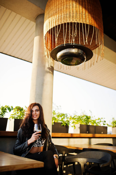 Young curly woman enjoying  her wine in a bar. - Фото, зображення