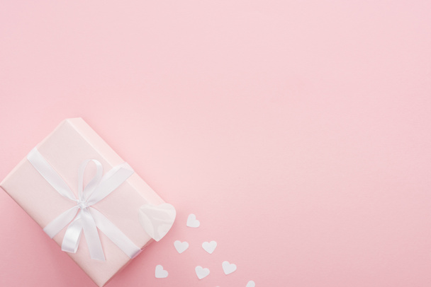 bovenaanzicht van geschenk doos en papieren hart op roze met kopie ruimte geïsoleerd - Foto, afbeelding