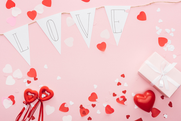 top view of valentines decorations and paper garland with 'love' lettering isolated on pink, st valentines day concept - Fotoğraf, Görsel