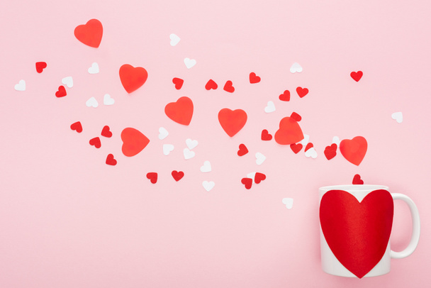 верхний вид бумаги сердца и чашки с наклейкой в форме сердца изолированы на розовый, День святого Валентина концепции
 - Фото, изображение