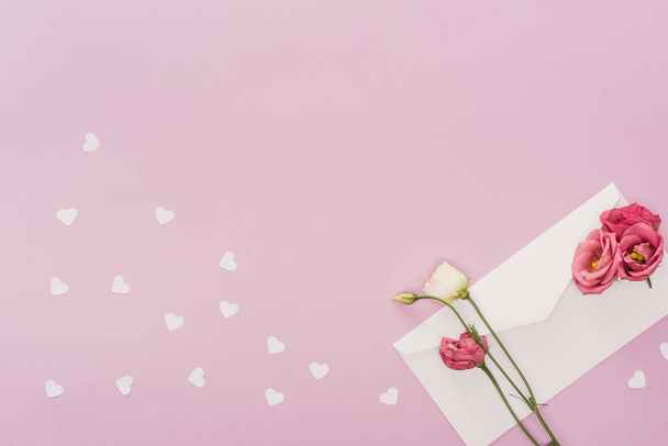 top view of envelope, flowers and paper hearts isolated on pink - Photo, Image