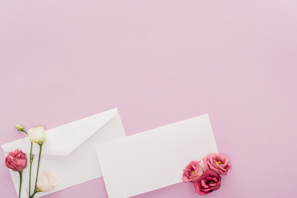 空白のカード、封筒、コピー スペースとピンクに分離された花のトップ ビュー - 写真・画像