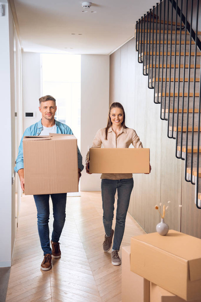 happy couple walking with boxes and smiling in new home  - Photo, Image