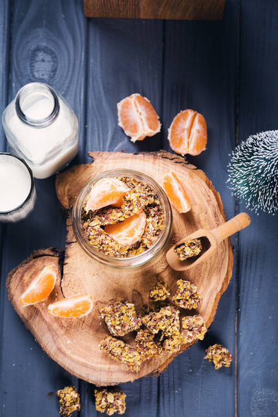 granola with mandarin and milk-healthy breakfast on wooden board - Photo, image