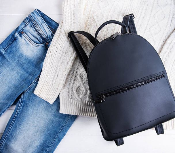 Black leather backpack and womens clothing, jeans and sweater - Photo, Image