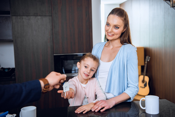 cropped view of broker giving house shaped key chain to cheerful mom and daughter - Fotografie, Obrázek