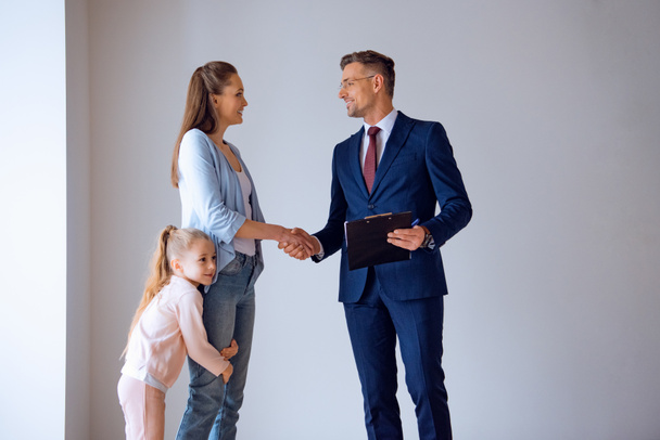 handsome broker shaking hands with attractive woman standing with cute daughter - Photo, Image