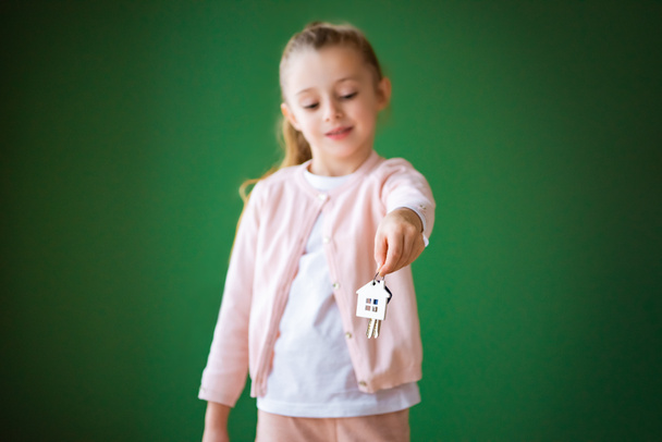 selective focus of kid holding house shaped key chain on green background - Fotó, kép