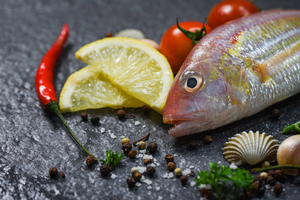 Pesce di mare piatto oceano cena gourmet pesce crudo fresco con erbe e spezie su sfondo scuro
  - Foto, immagini