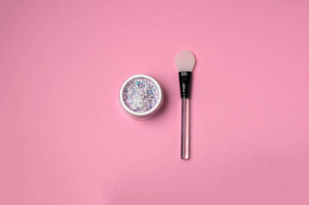Huid zorg schoonheid minimale concept - trendy glitter gezichtsmasker met siliconen spatel bovenaanzicht, roze achtergrond, kopie ruimte. Bloggen, social media. - Foto, afbeelding