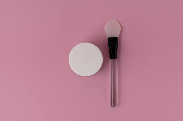 Skin care beauty minimal concept - face mask with silicone spatula top view, pink background, copy space - Foto, Imagen